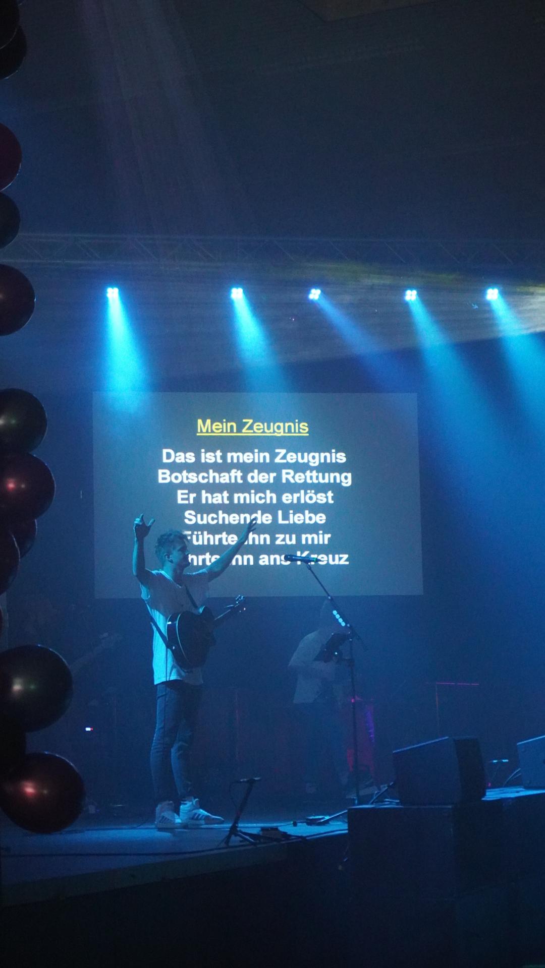Leadsänger hebt beim JUMIKO-Lobpreisabend 2023 die Hände zum Singen
