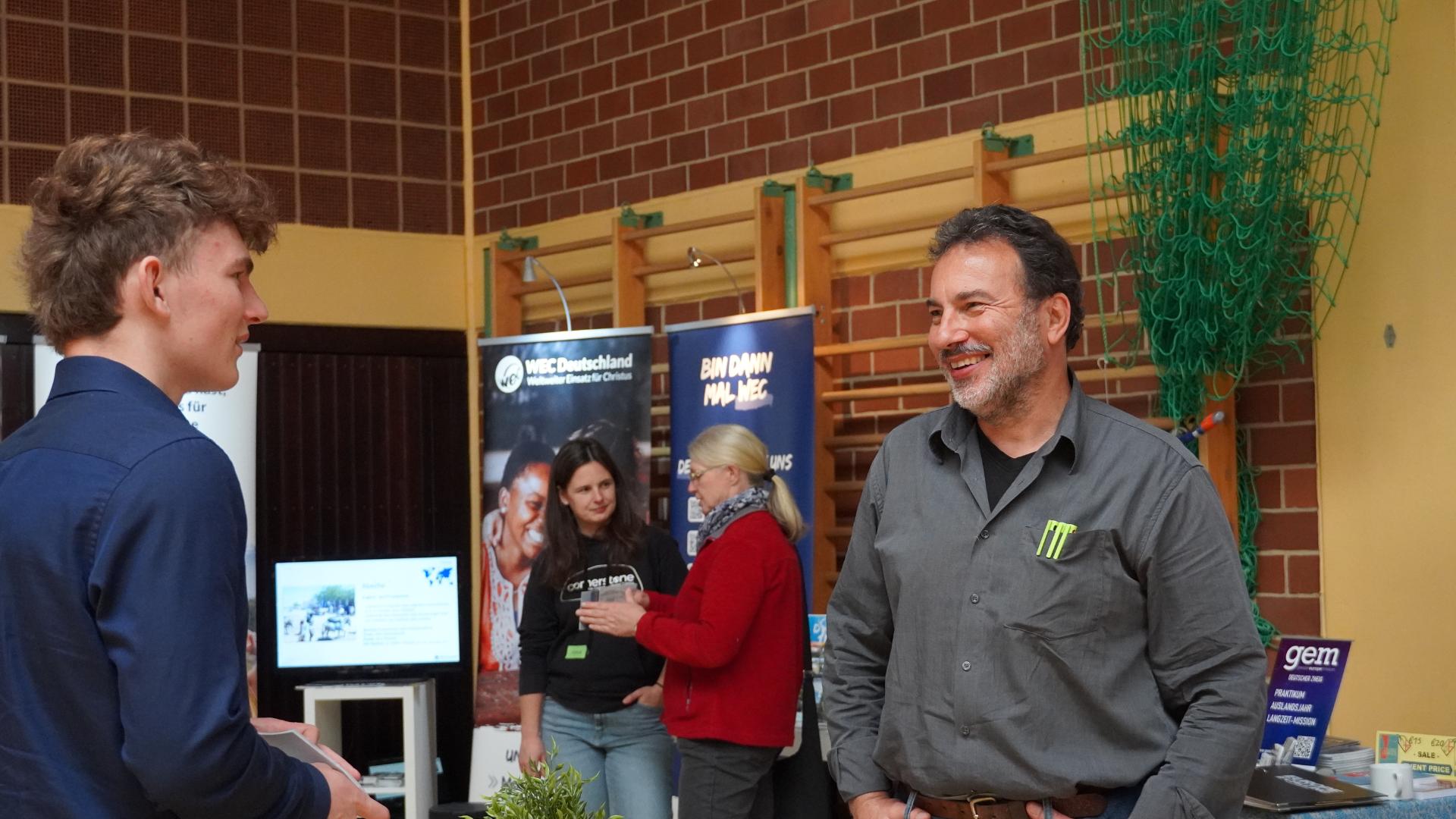 Besucher im Gespräch mit einem Missionar an einem Messestand